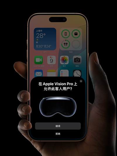 一只手拿着一部 iPhone。iPhone 屏幕显示一个窗口，窗口信息显示“在 Apple Vision Pro 上允许此客人用户？”，下方有“继续”和“拒绝”两个按钮。