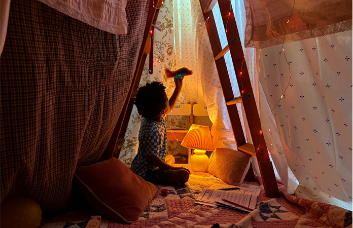 一张小孩坐在房间内毯子上玩耍的照片，使用相机低光功能拍摄