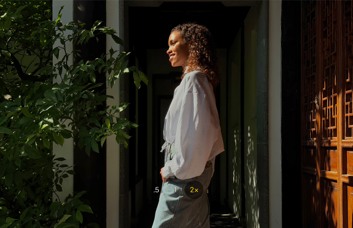 一张女子站立在庭院内的人像照，使用相机 2 倍长焦功能拍摄