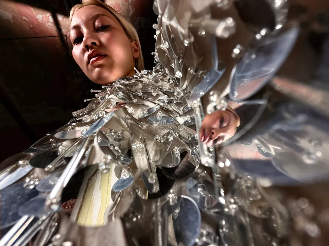 照片 app 展示 Pro 级拍摄系统在不同焦距下的拍摄视角，焦距切换到微距时，镜头拍摄一位女子身穿缀满银色亮片的礼服，展示亮片装饰的细节。